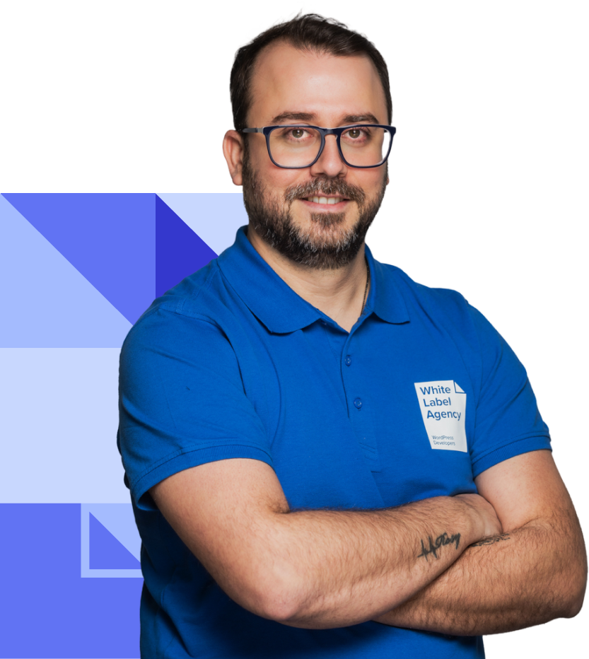 A man with dark hair, a beard, and glasses wearing a blue polo shirt with the White Label Agency logo. He is posing with his arms crossed.